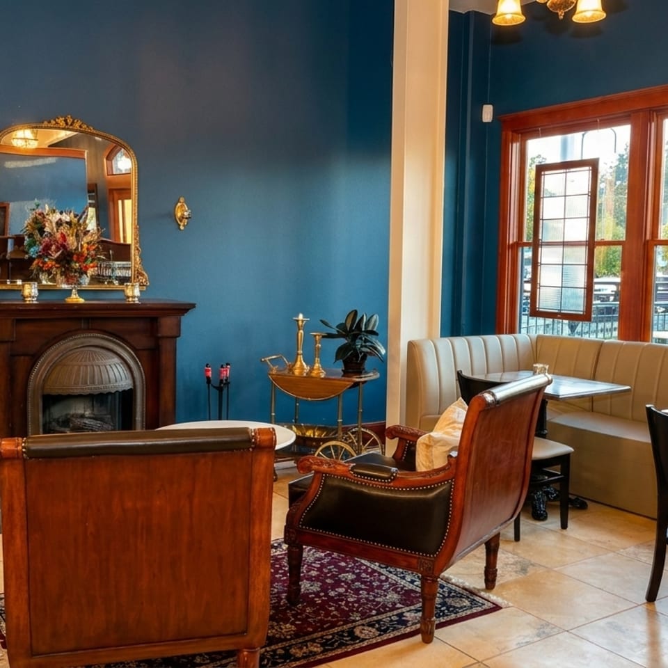 A cozy restaurant interior with blue walls, a fireplace, and seating areas including a window booth.
