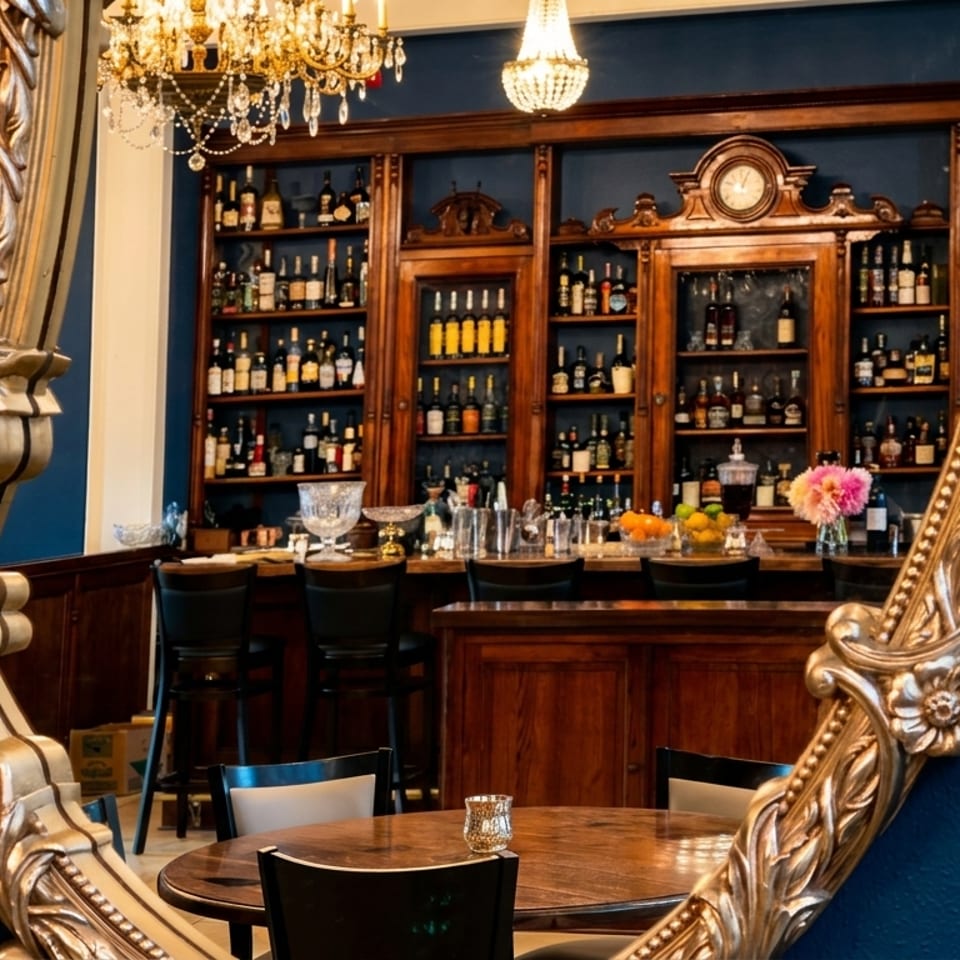 Ornate golden mirror reflecting a luxurious bar with dark wood shelves filled with bottles.